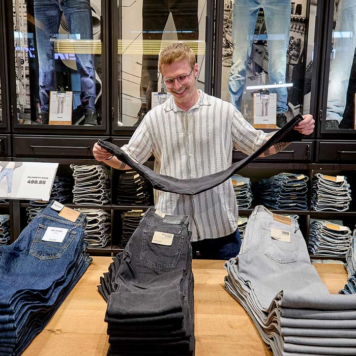 Medarbejder fra Jack & Jones i Herning lægger jeans på plads. 